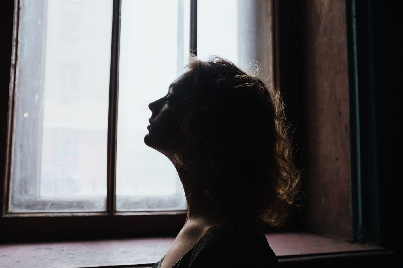 Silueta de una persona junto a una ventana con luz natural